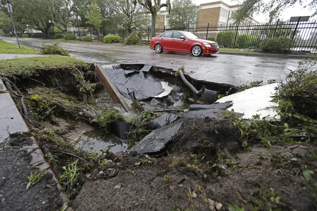 A car travels past a sinkhole in downtown Wilmington, N.C., after Hurricane Florence traveled through the area Sunday, September 16, 2018. (Photo by Chuck Burton/AP Photo)