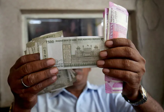 A cashier checks Indian rupee notes inside a room at a fuel station in Ahmedabad, September 20, 2018. (Photo by Amit Dave/Reuters)