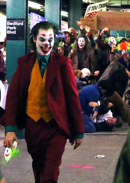 “JOKER” movie production tries to hide Joaquin Phoenix's clown make-up and green hair with umbrella and a long black cloth over his head as he was walking with the help of assistant and bodyguard to the set of “JOKER” filming at a Bronx train station on September 22, 2018. Production decorated entire train station with a Gotham look from 1980s with subway maps, garbage all over and background dressed up as clowns. Joaquin is later seen in full JOKER clown make-up and costume as he filmed a riot scene inside a Bronx train platform. (Photo by Splash News and Pictures)