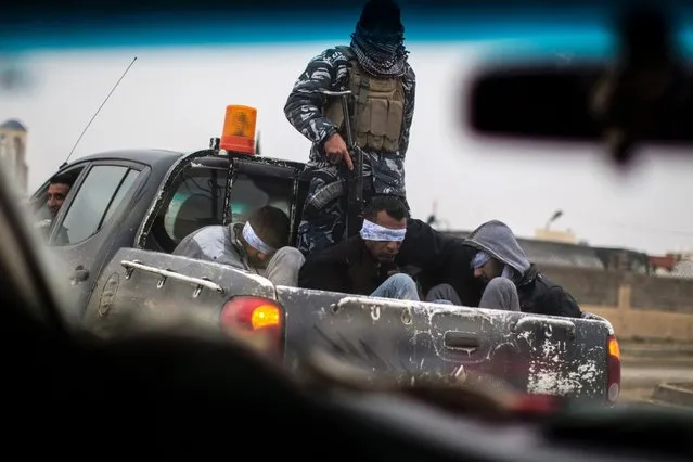 Christian militia fighters from the Nineveh Plain Protection Units (NPU) drive a pick- up truck in Qaraqosh (also known as Hamdaniya), transporting four men, allegedly members of the Islamic State (IS) group that were found inside a tunnel in Mosul, on December 20, 2016. (Photo by J.M. Lopez/AFP Photo)