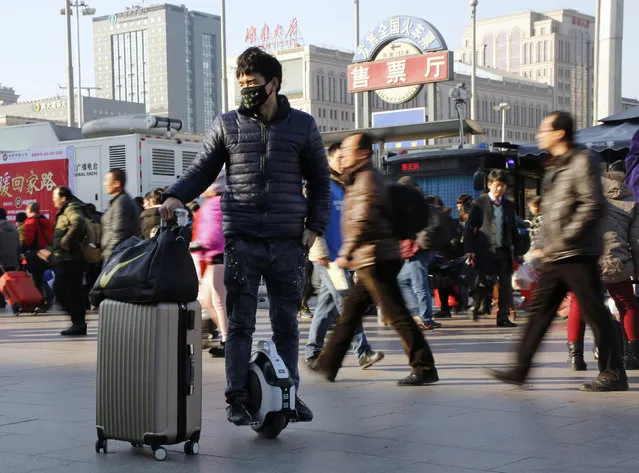 A man riding a personal mobility device holds his suitcase in front of the Beijing Railway Station during the travel rush ahead of the upcoming Spring Festival in Beijing, China, February 3, 2016. (Photo by Kim Kyung-Hoon/Reuters)
