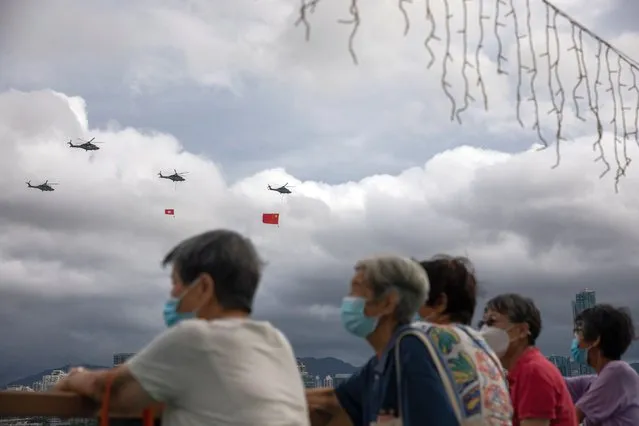 People watch a fly-by of Government Flying Services aircrafts displaying the People’ s Republic of China and the Hong Kong SAR flags over the Convention Centre in Hong Kong, China, 01 July 2022. Chinese President Xi Jinping is visiting the city to mark the 25th Anniversary of the establishment of the Hong Kong Special Administrative Region (HKSAR) of the People’s Republic of China on 01 July 2022. (Photo by Jerome Favre/EPA/EFE)