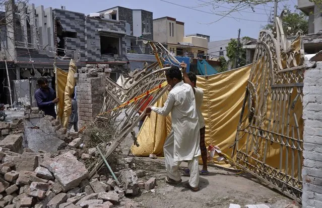 Residents remove a gate from their damaged house at the site of a car bombing Wednesday, in Lahore, Pakistan, Thursday, June 24, 2021. Pakistani security forces on Thursday arrested one of the alleged perpetrators of the car bombing that killed at least three people and wounded some 25 others near the residence of a jailed anti-India militant leader Hafiz Saeed, in the eastern city of Lahore, officials said. (Photo by K.M. Chaudary/AP Photo)