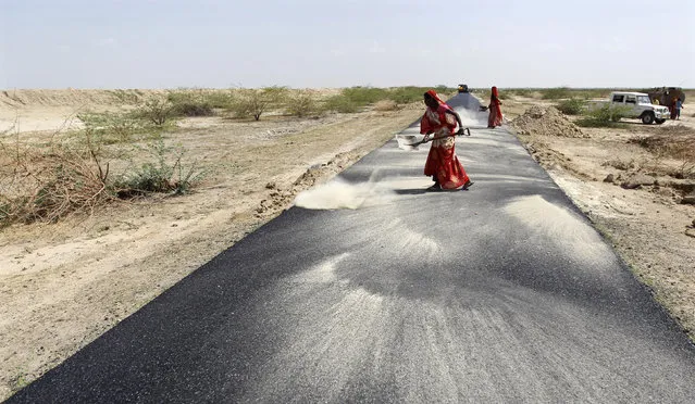 Women labourers throw dust on a road tarmac under construction at Bharadva village in Gujarat April 23, 2013. (Photo by Amit Dave/Reuters)