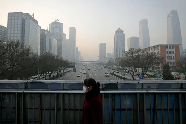 A woman wearing a mask for protection against air pollution walks on a pedestrian overhead bridge in Beijing as the capital of China is shrouded by heavy smog Monday, December 19, 2016. Engulfed in choking smog, some northern Chinese cities limited the number of cars on roads and temporarily shut down factories on Monday to cut down pollution during a national “red alert”. More than 700 companies stopped production in Beijing and traffic police were restricting drivers by monitoring their license plate numbers, state media reported. (Photo by Andy Wong/AP Photo)