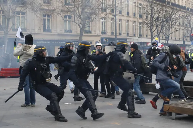 A photographer, right, runs away as riot police officers charge during a yellow vest protest, Saturday, February 2, 2019 in Paris. (Photo by Francois Mori/AP Photo)