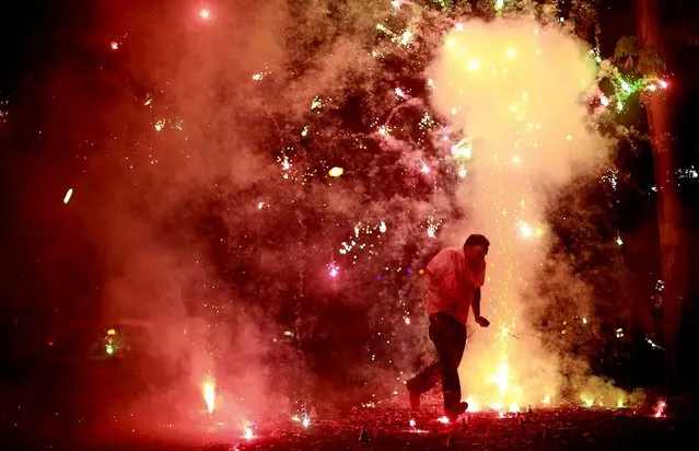 A man runs as firecrackers burst around him during the New Year celebrations in Mumbai, India. (Photo by Rafiq Maqbool/Associated Press)