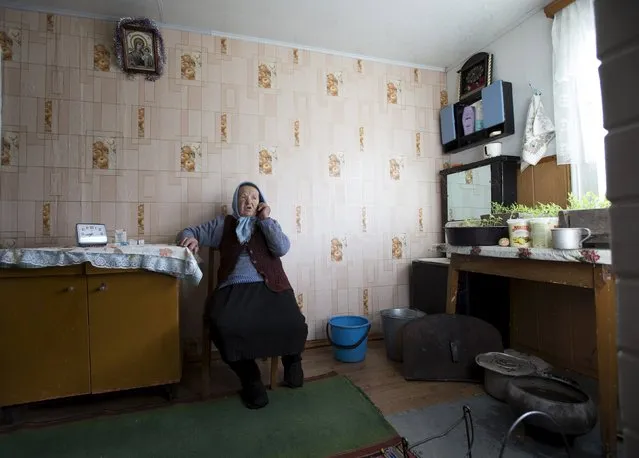 Nastia Pokolo, 74, speaks on a mobile phone at her house in the village of Babinets, southwest of the capital Minsk, April 17, 2015. (Photo by Vasily Fedosenko/Reuters)