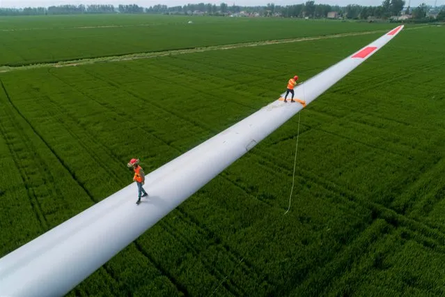Workers fasten wind turbine blades before hoisting work at Jinhu County on August 29, 2021 in Huai'an, Jiangsu Province of China. (Photo by He Jinghua/VCG via Getty Images)