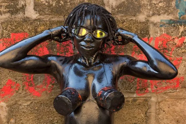 Susan Welchman, Senior Editor: “Pascal Maitre shot this image of Julie Djikley, a street artist in Kinshasa. Julie covered her body with engine oil and wore cans on her breasts as a statement about pollution in our environment created by cars and traffic. On several occasions she carried a gas tank on her back and a steering wheel in her hands, pushing a tiny car made of old cans. (Photo by Pascal Maitre/National Geographic)