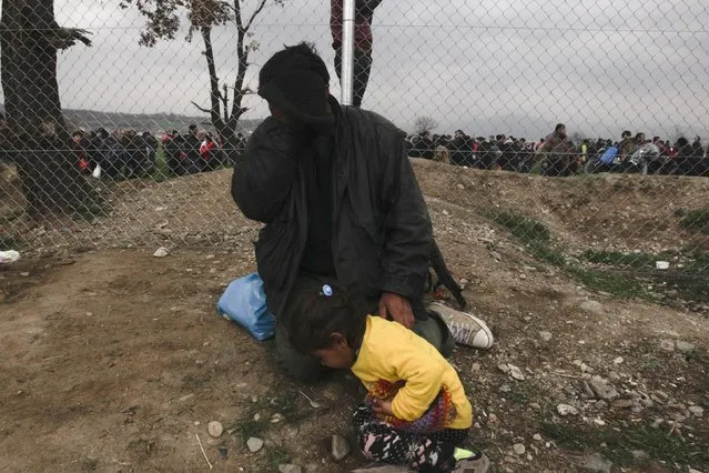A refugee and his daughter react from tear gas fired by the Macedonian police at stranded refugees and migrants who tried to bring down part of the border fence during a protest at the Greek-Macedonian border, near the Greek village of Idomeni, February 29, 2016. (Photo by Alexandros Avramidis/Reuters)