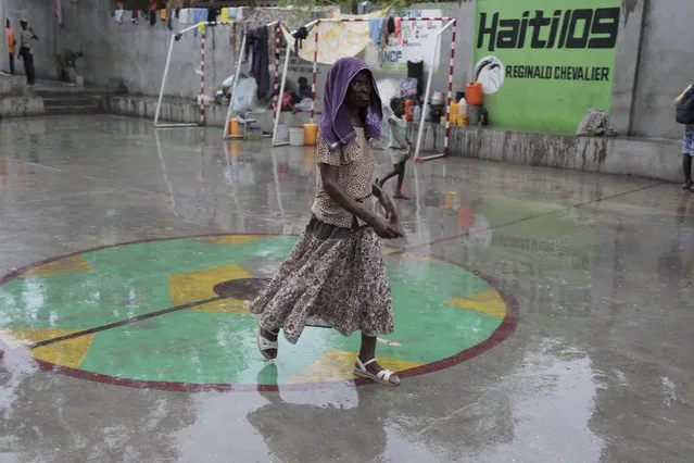 A woman displaced by the gang violence living at a school walks across a sports court amid the rain brought by Tropical Storm Franklin in Port-au-Prince, Haiti, Wednesday, August 23, 2023. (Photo by Odelyn Joseph/AP Photo)