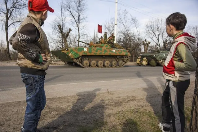 Two boys watch as a Russian-backed rebel convoy rolls along the street of Stakhanov, eastern in Stakhanov, Ukraine, Friday, April 24, 2015. (Photo by Mstyslav Chernov/AP Photo)