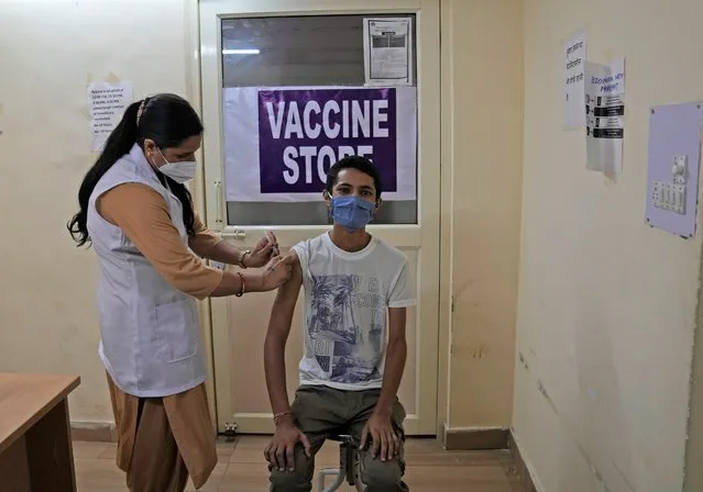 A health worker administers the vaccine for COVID-19 at a vaccination center in New Delhi, India, Tuesday, September 21, 2021. India, the world's largest vaccine producer, will resume exports and donations of surplus coronavirus vaccines in October after halting them during a devastating surge in domestic infections in April, the health minister said Monday. (Photo by Manish Swarup/AP Photo)