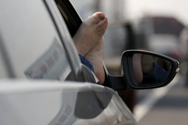 A man puts his bare feet on a window of a car while taking a nap as cars stop on Jinji Expressway located between Beijing and Tianjin, in a heavy traffic jam in Tianjin, China, March 2, 2016. (Photo by Kim Kyung-Hoon/Reuters)