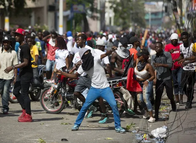 A demonstrator throws rocks at a house during a protest to demand the resignation of President Jovenel Moise and demanding to know how Petro Caribe funds have been used by the current and past administrations, in Port-au-Prince, Haiti, Thursday, February 7, 2019. (Photo by Dieu Nalio Chery/AP Photo)