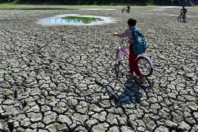 Children play at a dry reservoir for paddy fields due to drought in Kuta Cot Glie, Aceh province on January 24, 2024. (Photo by Chaideer Mahyuddin/AFP Photo)