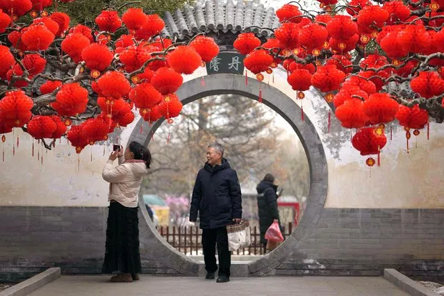 Residents take souvenir photo of a tree decorated with red lanterns ahead of the Chinese Lunar New Year at Ditan Park in Beijing, Sunday, February 4, 2024. Chinese will celebrate Lunar New Year on Feb. 10 this year which marks the Year of the dragon on the Chinese zodiac. (Photo by Andy Wong/AP Photo)