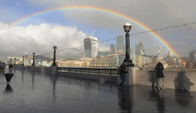 People walk along the Southbank as a rainbow appears over the city of London, on ebruary 4, 2014. (Photo by Nick Ansell/PA Wire)