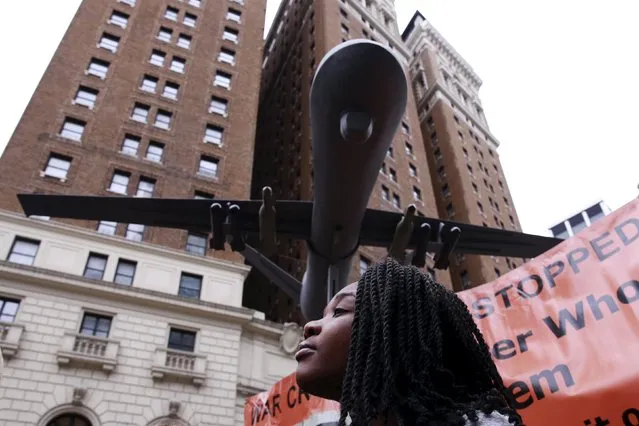A woman listens to speakers below a model of a drone at a demonstration to protest overseas wars the United States is involved in and actions of U.S. Republican presidential candidate Donald Trump in New York March 13, 2016. (Photo by Lucas Jackson/Reuters)
