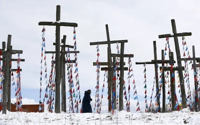 A woman walks on a hill with wooden crosses after a procession celebrating Palm Sunday in the town of Oshmiany, Belarus, March 20, 2016. (Photo by Vasily Fedosenko/Reuters)