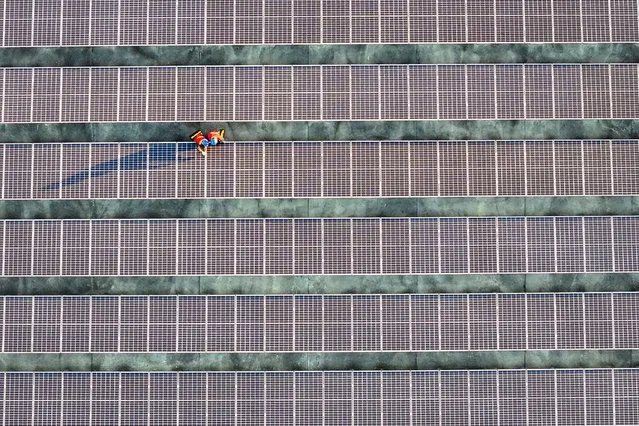 This photo taken on February 21, 2024 shows workers inspecting solar panels at a rooftop of a power plant in Fuzhou, in southern China's Fujian province. (Photo by AFP Photo/China Stringer Network)