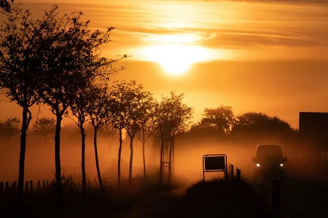 A car is driving on a country road in the fog as the sun rises in Schleswig-Holstein, Tating on October 7, 2021. (Photo by Bodo Marks/dpa)