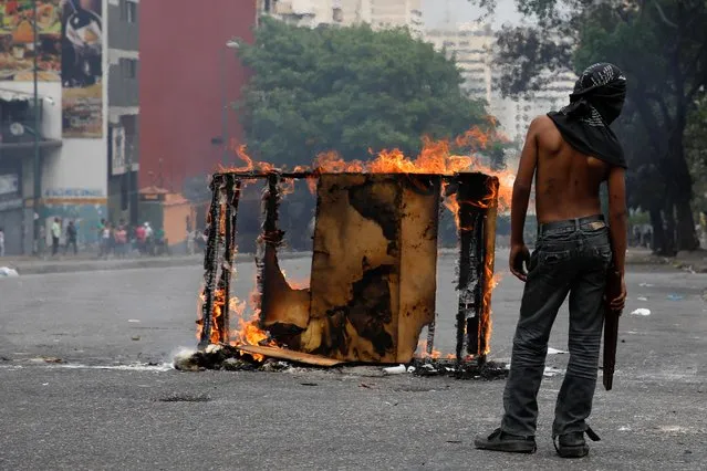 A demonstrator stands next to a burning barricade during a protest against the government of Venezuelan President Nicolas Maduro in Caracas, Venezuela March 31, 2019. (Photo by Carlos Garcia Rawlins/Reuters)