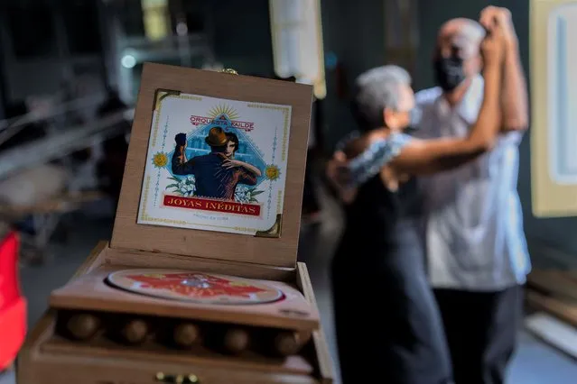 A couple dances next to the Failde Orchestra danzón music album “Joyas Inéditas”, featuring a tobacco box, in Matanzas, Cuba, Saturday, October 2, 2021. “Joyas Inéditas” was launched in two formats: one standard with a typical acrylic case and the other inserted in a wooden box that includes five Cuban cigars. (Photo by Ramón Espinosa/AP Photo)