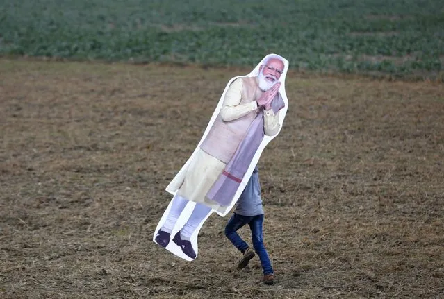 An onlooker runs away with the cut-out of Indian prime minister Narender Modi after the inauguration of Purvanchal expressway, in Sultanpur district, 140 kilometers (87 miles) from Lucknow, India, Tuesday, November 16, 2021. Indian Prime Minister Narendra Modi inaugurated the 211 miles (341) kilometers long expressway Tuesday. (Photo by Rajesh Kumar Singh/AP Photo)