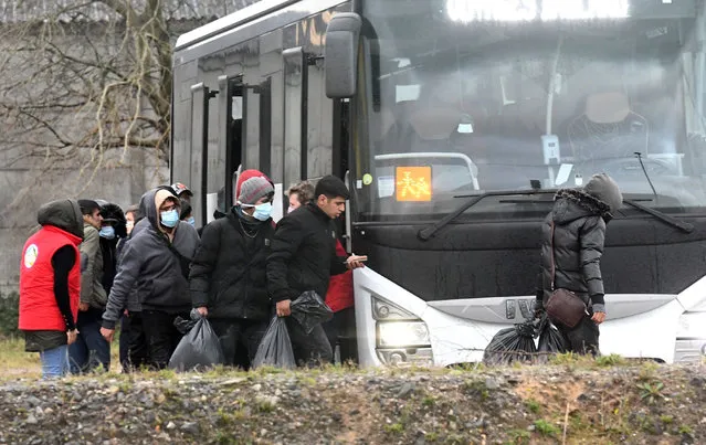 Migrants who were found soaked after a failed attempt to cross the Channel walk out from a shelter and take a bus to a warm place, in the rue des huttes in Calais on November 25, 2021. Britain and France were looking at new measures to limit migration across the Channel and break people-smuggling networks after at least 27 migrants trying to reach England drowned off the northern French coast. The disaster is the deadliest accident since the Channel became a hub for migrants from the Africa, the Middle East and Asia who have been increasingly using small boats to reach England from France since 2018. (Photo by Francois Lo Presti/AFP Photo)