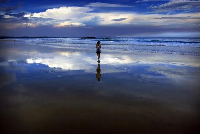 Storm clouds and dust can be seen in the sky above a woman as she walks at dusk along Mollymook Beach, south of Sydney March 5, 2014. (Photo by David Gray/Reuters)