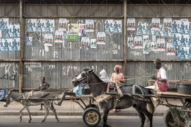 Carts ride past electoral posters in Dhara on March 21, 2024, as eighteen men and one woman are in the running on March 24 to become Senegal's fifth president. (Photo by Marco Longari/AFP Photo)