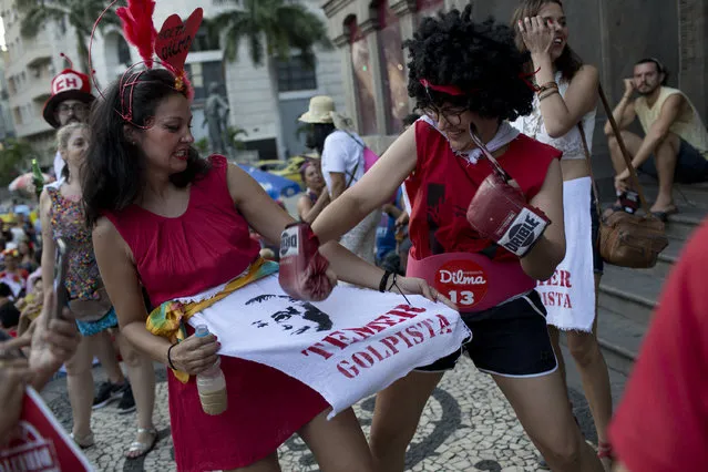 Revelers pretend to beat a sign that reads “Temer, coup leader” during the “Out Temer” carnival street party in Rio de Janeiro, Brazil, Friday, February 24, 2017. (Photo by Silvia Izquierdo/AP Photo)