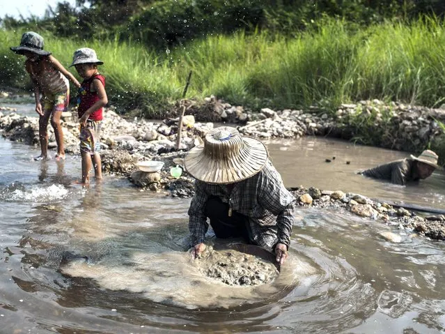 Petong (C) and Hue (R) look for gold as their children play in the water in Lampang. (Photo by Borja Sanchez-Trillo/Getty Images)