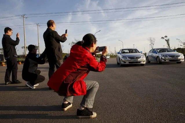 Visitors take pictures of Changan Automobile's self-driving cars, which are manually driven, as they complete a test drive from Chongqing to Beijing to arrive at Changan Automobile's Beijing headquarters, China, April 16, 2016. (Photo by Kim Kyung-Hoon/Reuters)