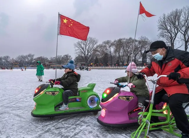 Children ride in cars on the ice at an outdoor rink on Shichahai Lake at Houhai on January 18, 2022 in Beijing, China. (Photo by Kevin Frayer/Getty Images)