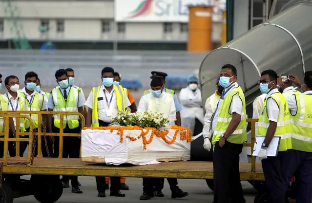 Sri Lankan air port workers stand next to a casket carrying remains of Priyantha Kumara, a Sri Lankan employee who was lynched by a Muslim mob in Sialkot last week after unloading it from an aircraft in Colombo, Sri Lanka, Monday, December 6, 2021. (Photo by Eranga Jayawardena/AP Photo)