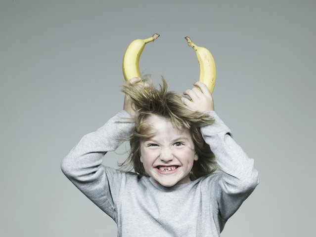 Boy (6-7) holding two banana on head, smiling, close-up. (Photo by Flashpop/Getty Images)
