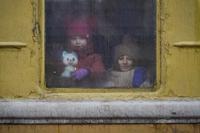 Children look out the window of an unheated Lviv bound train, in Kyiv, Ukraine, Thursday, March 3, 2022. Ukrainian President Volodymyr Zelenskyy's office says a second round of talks with Russia aimed at stopping the fighting that has sent more than 1 million people fleeing over Ukraine's borders, has begun in neighboring Belarus, but the two sides appeared to have little common ground. (Photo by Vadim Ghirda/AP Photo)