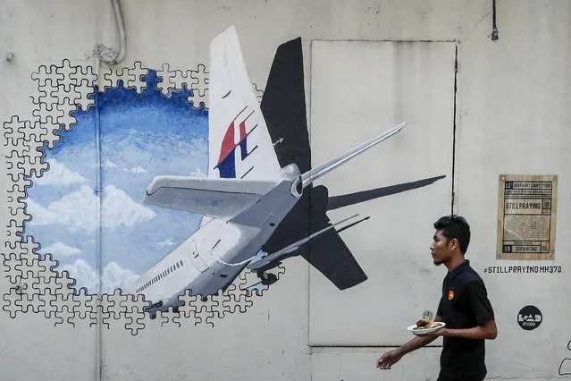 In this Tuesday, February 23, 2016, file photo, a waiter walks past a mural of flight MH370 in Shah Alam outside Kuala Lumpur, Malaysia. Malaysia's government said Thursday, May 12, 2016, that two more pieces of debris, discovered in South Africa and Rodrigues Island off Mauritius, were “almost certainly” from Flight 370, which mysteriously disappeared more than two years ago with 239 people on board. (Photo by Joshua Paul/AP Photo)