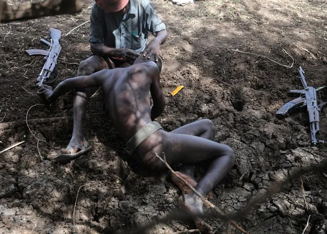 A Turkana warrior cuts the hair of his friend while they protect cattle from Nyangatom warriors in Ilemi Triangle, Kenya, July 19, 2019. (Photo by Goran Tomasevic/Reuters)