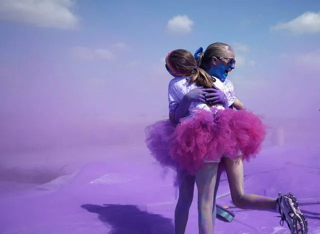 Competitors hug after running through colored powder at the Orange County Color 5K Run in Irvine, California May 10, 2014. (Photo by Lucy Nicholson/Reuters)