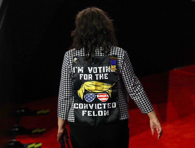 A person wearing a coat supporting former President Donald Trump walks ahead of Day 2 of the RNC, at the Fiserv Forum in Milwaukee, Wisconsin on July 16, 2024. (Photo by Mike Segar/Reuters)