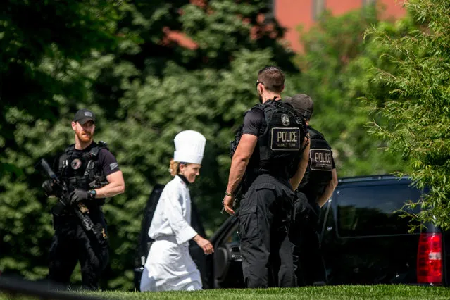 A White House chef walks past Secret Service agents as they stand on the North Lawn of the White House in Washington, Friday, May 20, 2016, after the White House was placed on security alert after shooting on street outside. (Photo by Andrew Harnik/AP Photo)