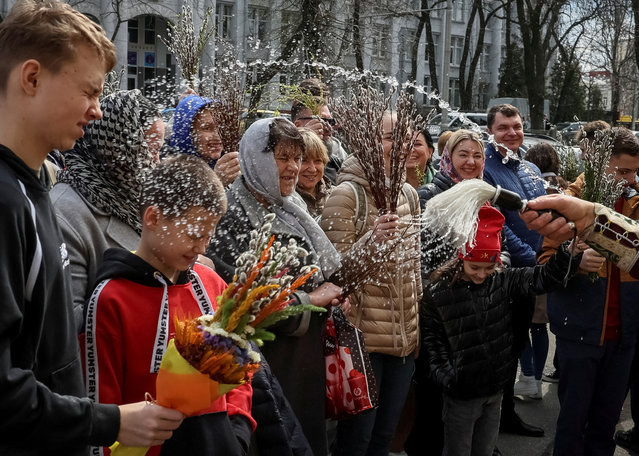 An Orthodox priest sprays holy water on believers after a service which marks the Orthodox feast of Palm Sunday, amid Russia's invasion of Ukraine, in Kyiv, Ukraine on April 9, 2023. (Photo by Gleb Garanich/Reuters)