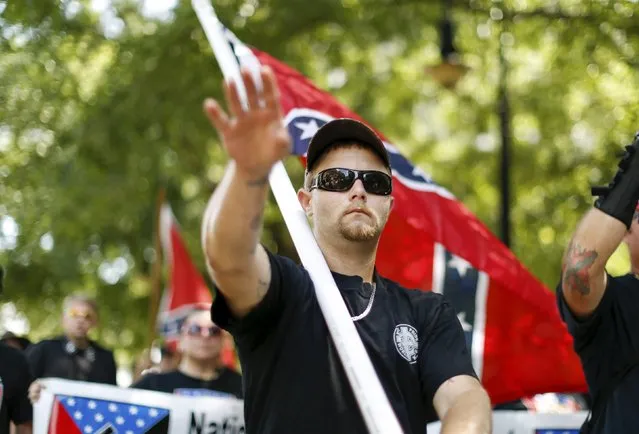 A member of the Ku Klux Klan gestures as he marches during a rally at the statehouse in Columbia, South Carolina July 18, 2015. A Ku Klux Klan chapter and an African-American group planned overlapping demonstrations on Saturday outside the South Carolina State House, where state officials removed the Confederate battle flag last week. (Photo by Chris Keane/Reuters)