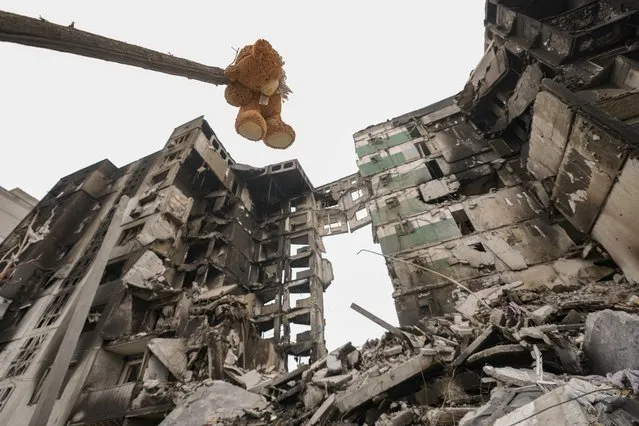 A teddybear hangs from a branch of a torn tree outside an apartment building destroyed during fighting between Ukrainian and Russian forces in Borodyanka, Ukraine, Tuesday, April 5, 2022. Ukrainian President Volodymyr Zelenskyy accused Russian troops of gruesome atrocities in Ukraine and told the U.N. Security Council on Tuesday that those responsible should immediately be brought up on war crimes charges in front of a tribunal like the one set up at Nuremberg after World War II. (Photo by Vadim Ghirda/AP Photo)