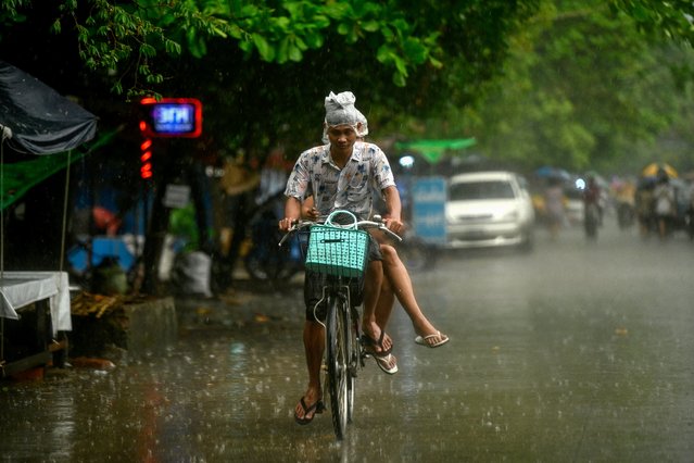 A man uses a plastic bag to cover his head during the rain in Yangon on May 5, 2024. (Photo by Sai Aung Main/AFP Photo)