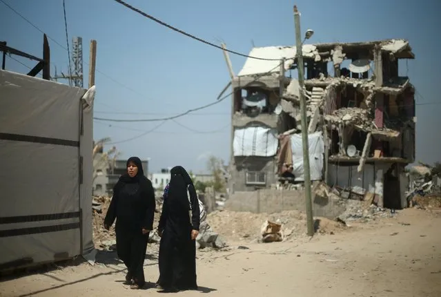 Palestinian women walk in front of a house that witnesses said was destroyed by Israeli shelling during a 50-day war last summer, in the east of Gaza City May 6, 2015. (Photo by Mohammed Salem/Reuters)